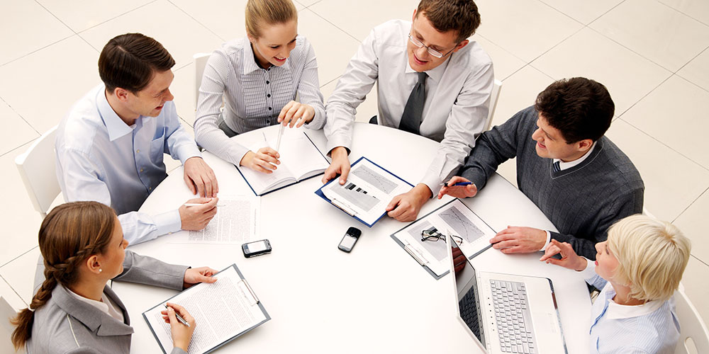 Pessoas reunidas para levantamento de requisitos em volta de uma mesa