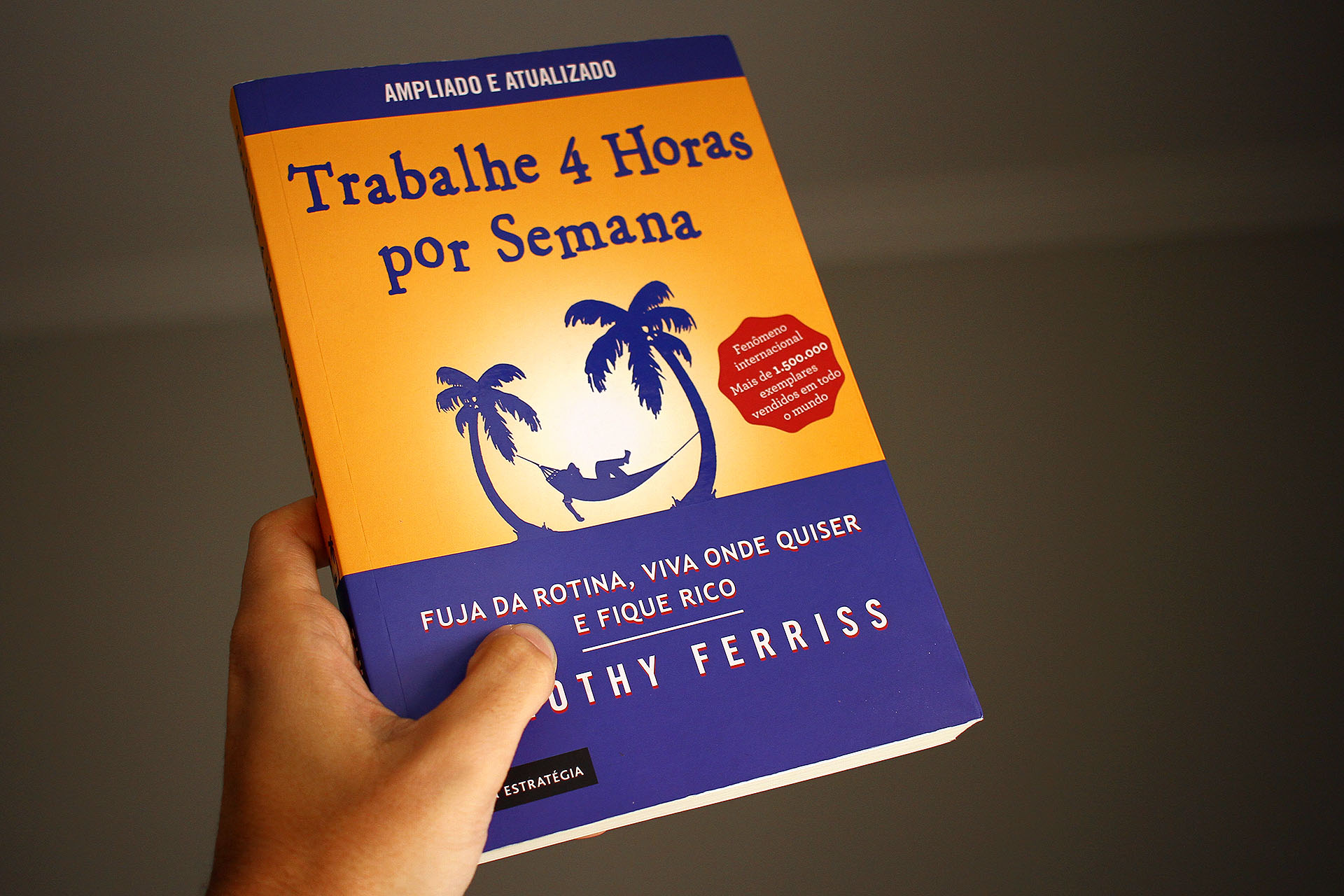 Livro Trabalhe 4 Horas por semana erguido por uma mão