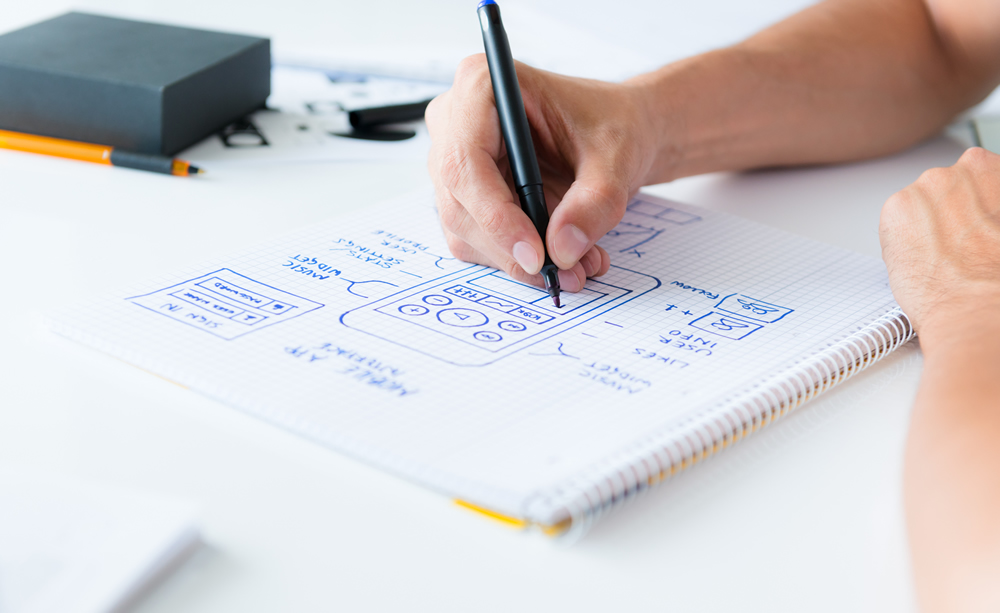 Homem rascunhando em papel o desenho de um aplicativo